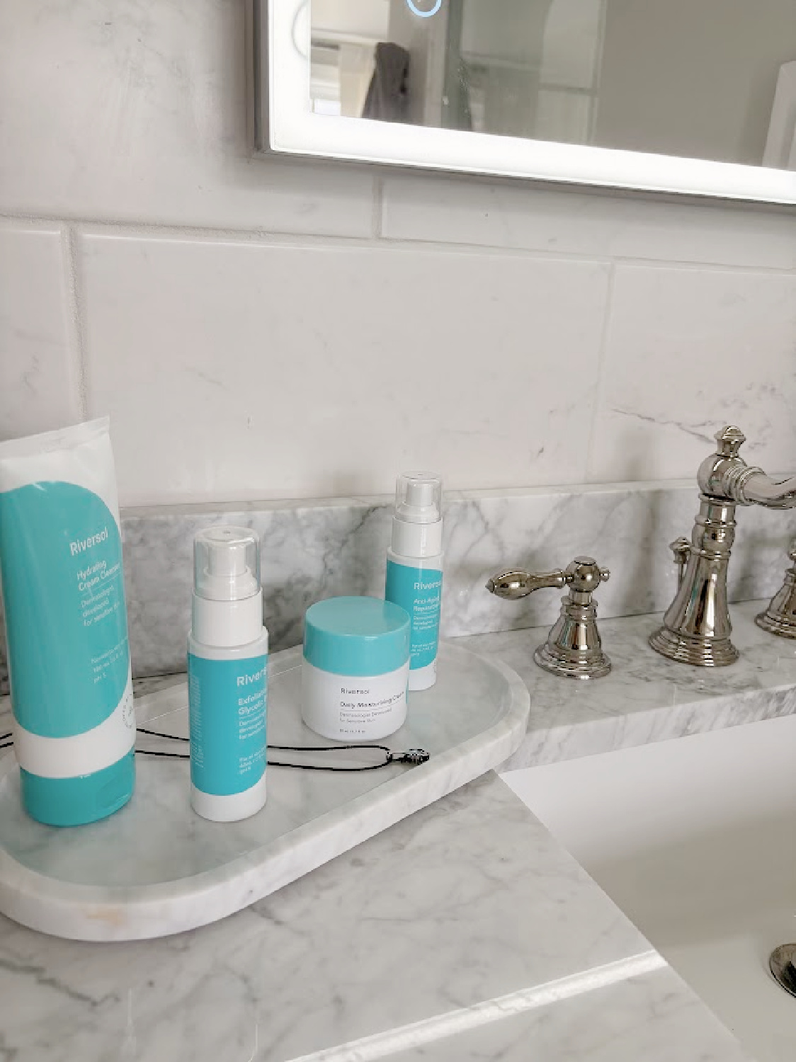 Hello Lovely's bath vanity with Riversol skincare products on oval tray.
